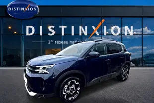 Vue 3/4 avant droite d'un Citroën C5 Aircross bleu eclipse avec jantes alu devant une vitrine Distinxion.