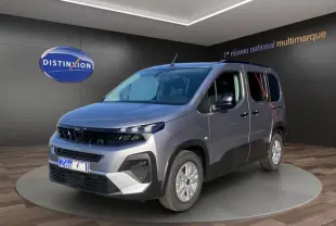 Peugeot Rifter gris clair en 3/4 avant droit, avec calandre noire et jantes argentées en showroom.