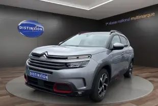 Vue 3/4 avant d'un Citroën C5 Aircross gris clair avec détails rouges sur la calandre et jantes bicolores.