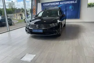 Volkswagen Passat SW noir nacré vue 3/4 avant droit en showroom avec barres de toit et calandre chromée.