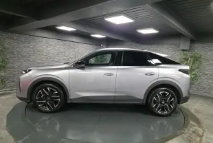 Vue de profil côté gauche d’un Peugeot 3008 gris métallisé avec jantes alliage noires et toit noir dans un showroom.