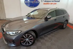 BMW Série 3 318d gris clair vue 3/4 avant droit, avec jantes alliage et phares LED allumés.