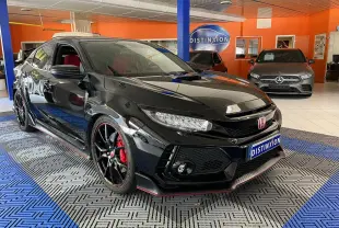 Honda Civic Type R noire vue en 3/4 avant droit dans un showroom, avec jantes noires et étriers rouges visibles.