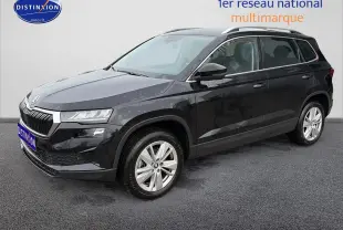 Vue 3/4 avant d’un Skoda Karoq noir 2025 avec jantes alu et barres de toit visibles sur fond neutre.
