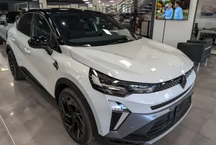 Renault Captur E-Tech hybride blanc nacré avec toit noir, vue 3/4 avant droit en intérieur showroom.
