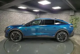 Profil droit d'une Peugeot 408 hybride rechargeable bleu métallisé, avec jantes alliage 19 pouces et vitres teintées.