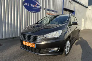 Ford C-MAX 1.6 TDCI 120 Titanium gris foncé vue 3/4 avant avec plaque "OCCASION" devant un bâtiment industriel.