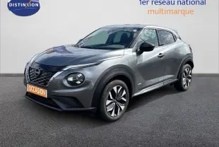 Nissan Juke Hybrid gris squale métal en 3/4 avant droit, avec jantes distinctives et calandre noire brillante.