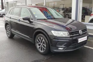Volkswagen Tiguan 2.0 TDI noir nacré vu en 3/4 avant droit sous la pluie, avec jantes alliage et feux LED.