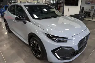 Renault Clio VI gris Rafale vue 3/4 avant droit, avec jantes noires bicolores et rétroviseurs noirs brillants.