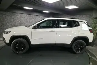Vue de profil côté gauche d'un Jeep Compass blanc avec jantes noires et détails noirs contrastants en intérieur.