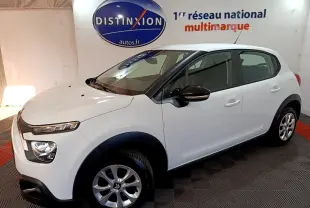 Vue 3/4 avant droit d'une Citroën C3 blanche avec protections noires et jantes alliage en showroom.