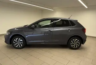 Vue de profil côté gauche d'une Volkswagen Polo gris cendre avec jantes alliage bicolores et vitres teintées, en intérieur.