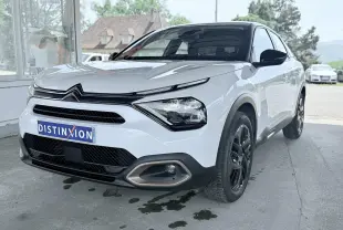 Citroën C4 blanc vue 3/4 avant droit, avec calandre noire et jantes noires contrastantes.