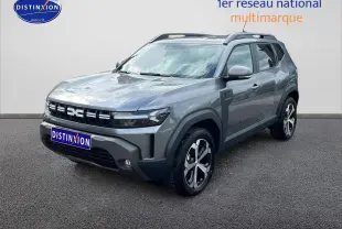 Dacia Duster gris schiste en 3/4 avant droit avec barres de toit et jantes alu visibles.