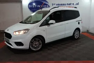Vue 3/4 avant droite d’un Ford Grand Tourneo Connect blanc avec phares allumés dans un showroom intérieur.
