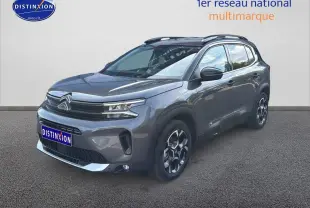 Vue 3/4 avant droit d'un Citroën C5 Aircross gris platinium avec barres de toit et jantes alu distinctives.