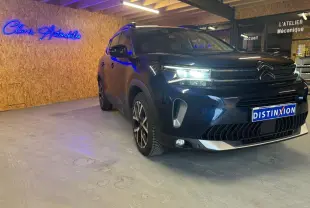Vue 3/4 avant droite du Citroën C5 Aircross bleu avec barres de toit et jantes alu 18 pouces dans un showroom.