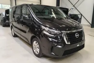 Nissan Primastar noir vue 3/4 avant droit dans un garage, avec calandre chromée et phares LED distinctifs.