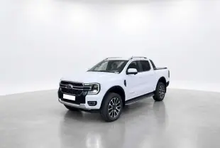 Ford Ranger blanc glacier en 3/4 avant droit avec jantes alu 20 pouces et barres de toit visibles.