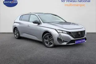 Peugeot 308 gris en 3/4 avant droit, mettant en valeur sa calandre distinctive et ses phares LED fins.