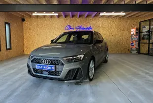 Audi A1 Sportback gris 3/4 avant droit, finition S-Line avec calandre noire et jantes alliage visibles.