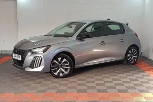 Peugeot 208 Hybrid gris clair vue de profil droit en intérieur, avec jantes stylisées et phares LED allumés.