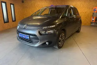 Vue 3/4 avant droit d'une Citroën C4 Picasso gris métallisé dans un showroom avec éclairage intérieur.
