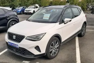 SEAT Arona blanc avec toit noir, vue 3/4 avant droit, stationné sur un parking extérieur.
