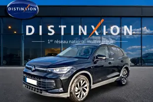Volkswagen Tiguan noir en 3/4 avant droit, avec jantes spécifiques et calandre moderne devant showroom Distinxion.