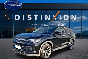 Volkswagen Tiguan noir vue 3/4 avant droit, avec jantes alliage et calandre marquée devant un showroom Distinxion.