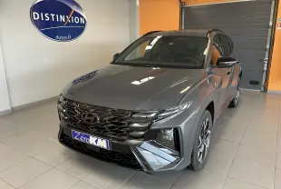 Vue 3/4 avant d'un Hyundai Tucson gris Ecotronic avec calandre noire et jantes alliage en intérieur showroom.