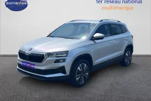 Vue 3/4 avant d’un Skoda Karoq 2025 gris argenté avec jantes bi-ton et calandre noire distinctive.