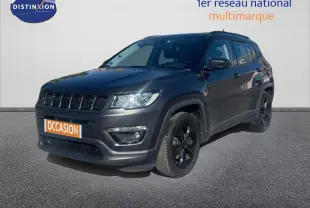 Jeep Compass gris foncé en 3/4 avant droit, version Brooklyn Edition avec jantes noires et calandre distinctive.