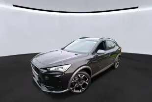 Vue 3/4 avant droite d'un CUPRA Formentor 1.4 E-HYBRID 245 VZ noir, avec jantes alliage et phares LED allumés.