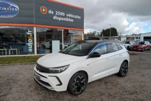 Opel Grandland blanc métallisé en 3/4 avant droit avec toit noir et jantes alliage noires sur parking.