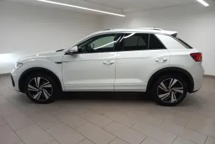 Vue de profil côté gauche du Volkswagen T-Roc blanc pur 2025, avec jantes distinctives R-Line et toit noir contrasté.