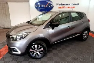 Renault Captur Business gris foncé vu en 3/4 avant droit dans un showroom avec logo Distinxion en arrière-plan.