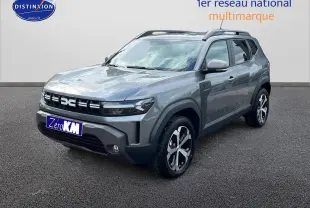 Vue 3/4 avant droite d'un Dacia Duster gris schiste 2025 avec jantes alu et barres de toit visibles.
