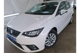 Vue 3/4 avant droite d'une SEAT Ibiza blanche 5 portes exposée en showroom avec jantes alliage et calandre noire.