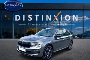 Skoda Kamiq gris graphite en 3/4 avant droit, avec jantes alu noires et toit panoramique visible.