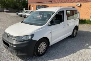 Volkswagen Caddy blanc Candy vue 3/4 avant droit, avec pare-chocs noir et portes coulissantes visibles.