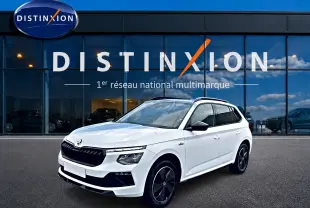 SKODA KAMIQ blanc nacré en 3/4 avant, avec jantes noires et toit panoramique visible devant une vitrine Distinxion.