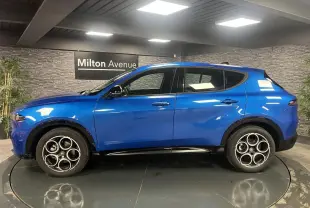 Vue de profil côté gauche d'un Alfa Romeo Tonale bleu métallisé avec jantes alliage 18 pouces et rétroviseurs noirs.