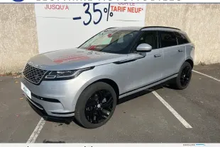 Range Rover Velar gris en 3/4 avant droit, avec jantes noires brillantes et calandre distinctive noire.