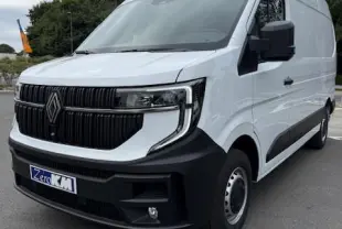 Renault Master blanc en 3/4 avant droit, avec calandre noire et feux LED distinctifs sur route grise.