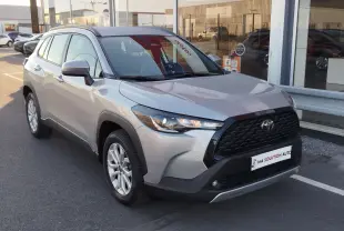 Toyota Corolla Cross gris minéral vue 3/4 avant droit, calandre noire et jantes alliage visibles.