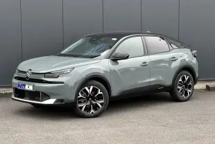 Citroën C4 NV Hybrid 145 e-DSC6 Max en Manhattan Green avec toit noir, vue 3/4 avant droit sur fond urbain.