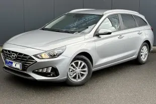 Hyundai i30 SW T-GDI 120 Modern gris argent en 3/4 avant droit, avec jantes alliage et feux allumés.
