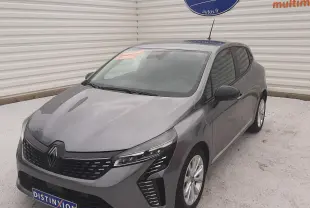 Renault Clio V gris schiste vue 3/4 avant droit, avec calandre noire et feux LED distinctifs, sur parking extérieur.